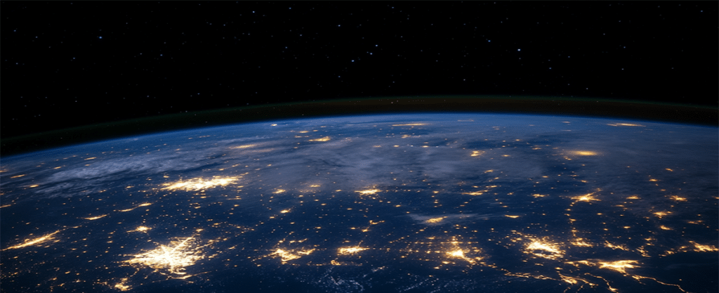 Dark sky image, overhead shot of the planet Earth, lights shining for various places from the planet.